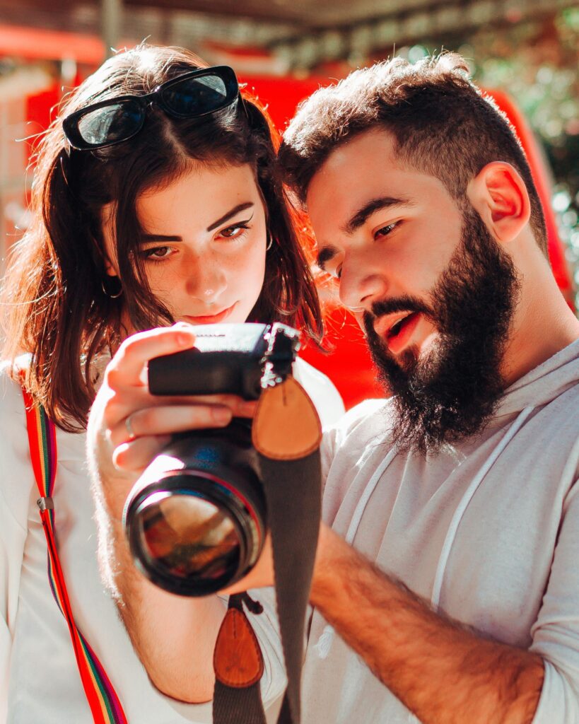 A focused and serious duo reviewing photographs on a DSLR camera outdoors.