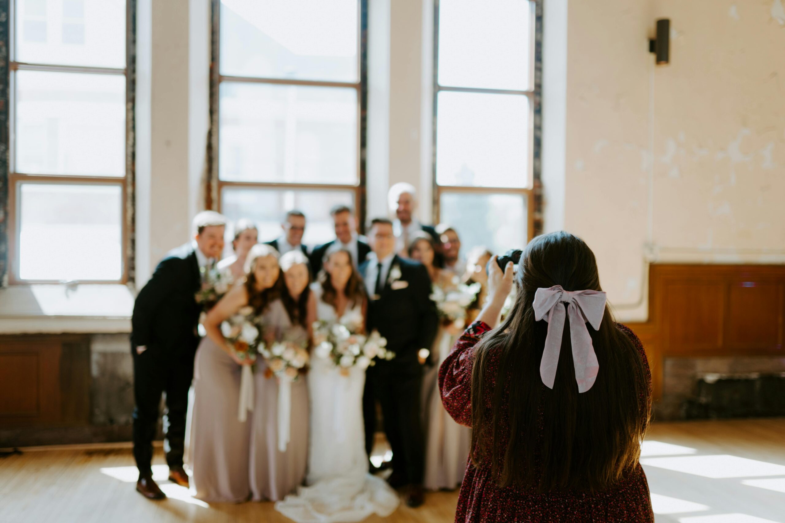 A photographer captures a memorable wedding moment with the bride, groom, and wedding party indoors.