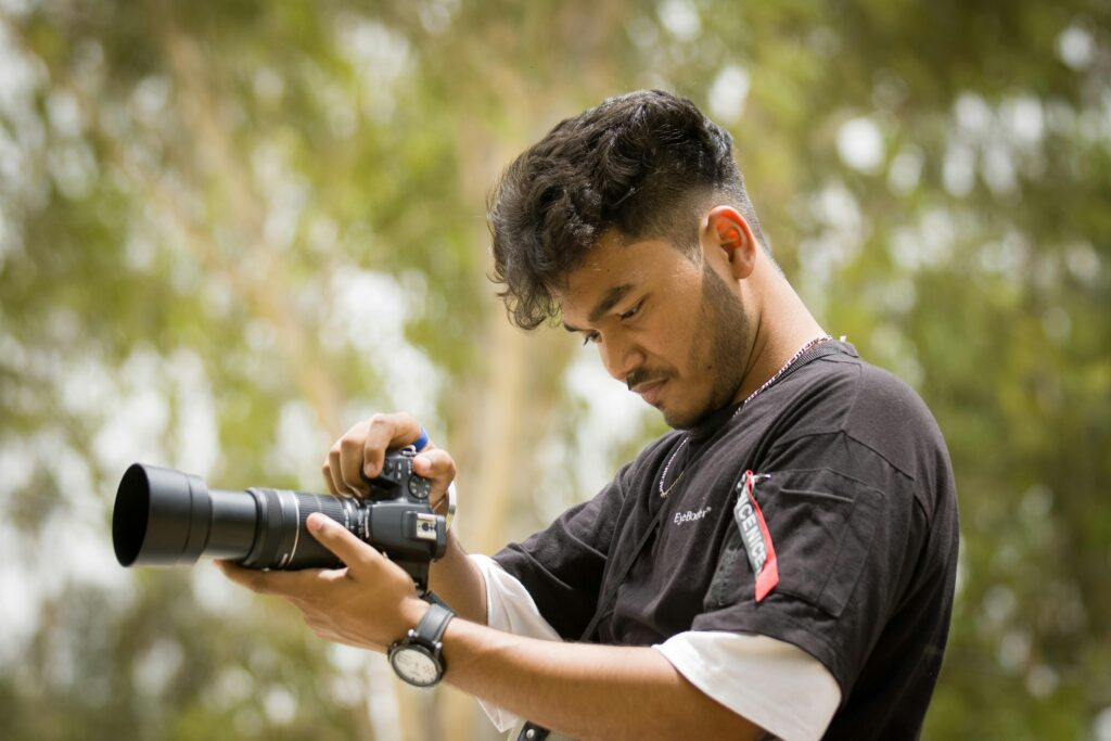 A young male photographer setting up his camera outdoors, focused and ready to capture the moment.