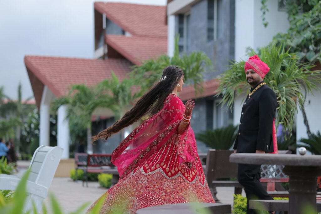 Elegant couple at an outdoor Indian wedding in traditional attire.
