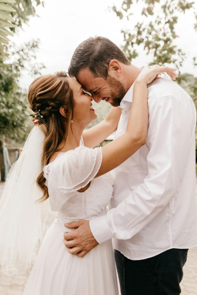 Bride and groom embracing tenderly outdoors in a romantic moment.