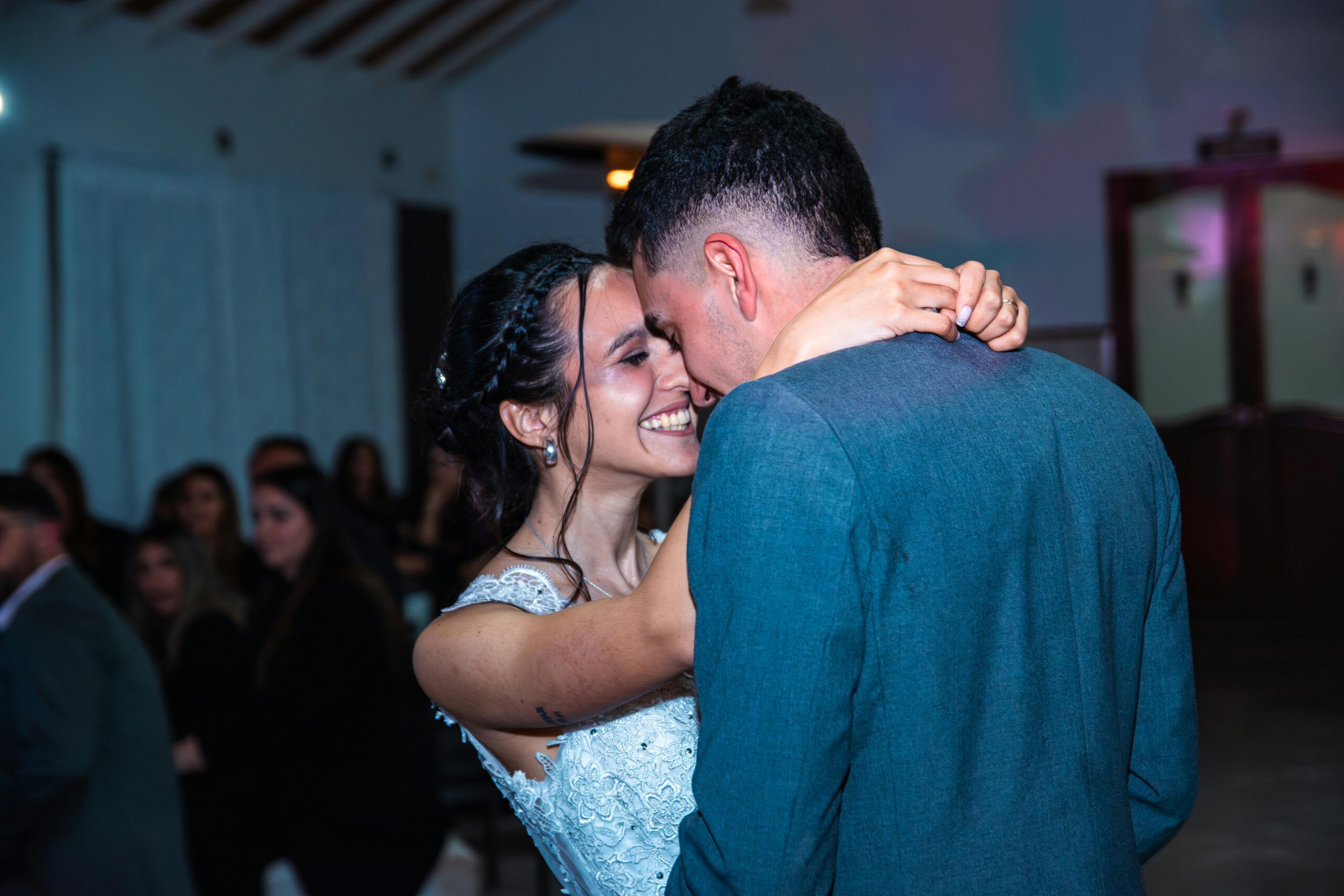 Joyful bride and groom embrace during their wedding dance at a lively celebration.